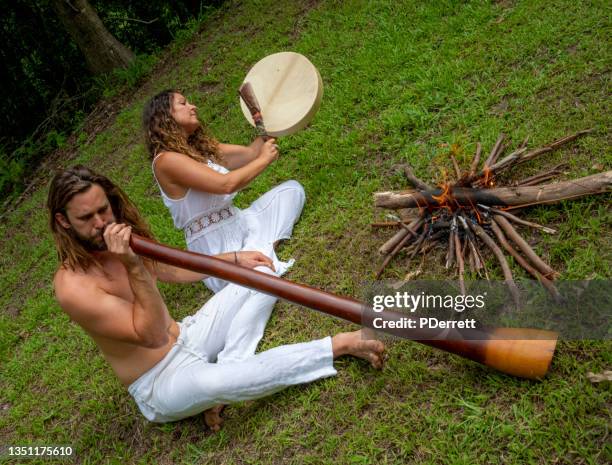 alternative young couple play didgeridoo and beat drum. - didgeridoo stock pictures, royalty-free photos & images