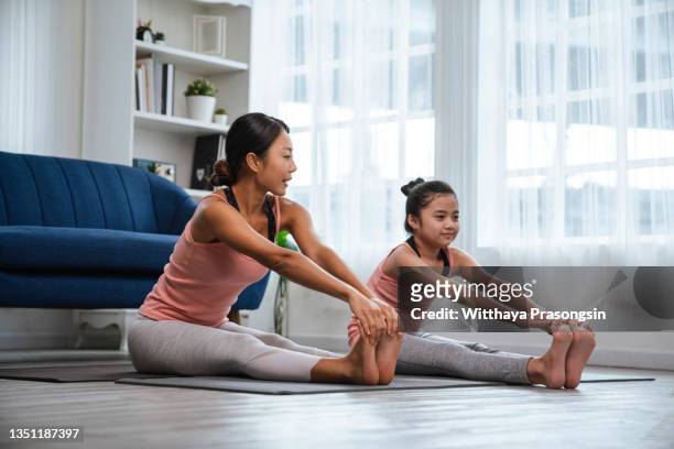 mother and little girl are doing sport exercises at home - zuidoost aziatische etniciteit stockfoto's en -beelden