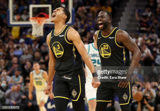 Jordan Poole and Draymond Green of the Golden State Warriors react after Poole made a three-point basket against the Charlotte Hornets in the first...