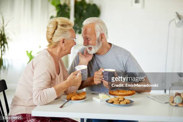 a happy senior couple enjoying breakfast together at home - loyalty stock pictures, royalty-free photos & images
