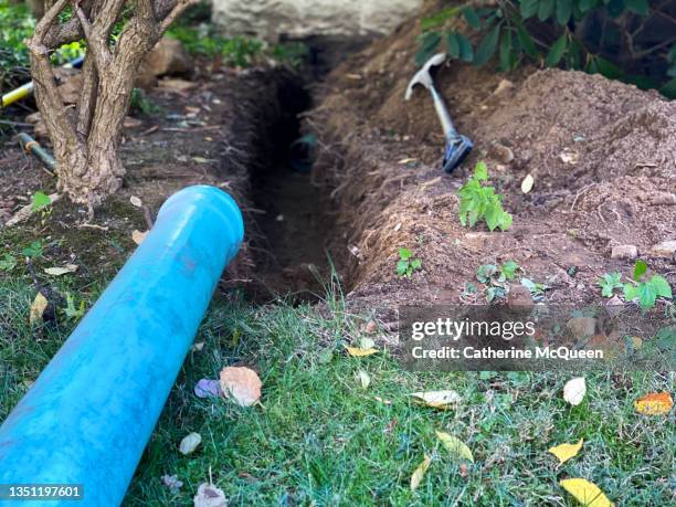 digging trench for installation of new outdoor drain pipe to prevent future flooding in home - drain stock pictures, royalty-free photos & images