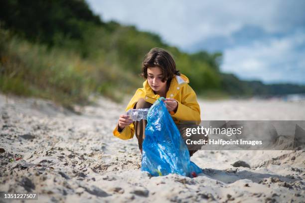 preteen ecological girl cleaning beach from plastic waste. - alleen één meisje stockfoto's en -beelden