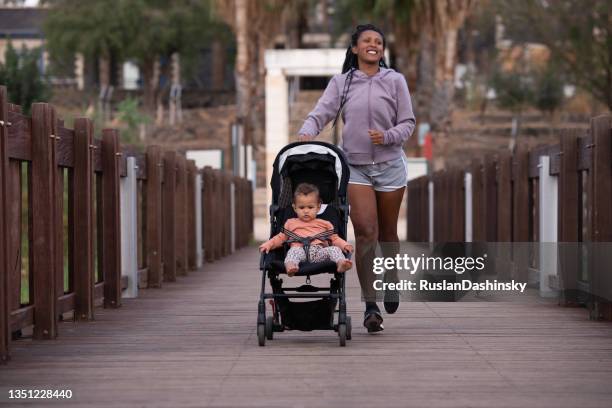 mother with baby stroller running in the park. - the stroller stock pictures, royalty-free photos & images