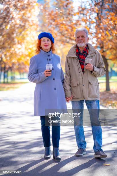 loving senior couple enjoy a walk together on a autumn day - mature couple winter outdoors stock pictures, royalty-free photos & images