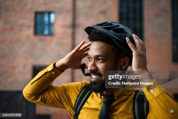 portrait of man commuter putting on cycling helmet, sustainable lifestyle. - sports helmet foto e immagini stock