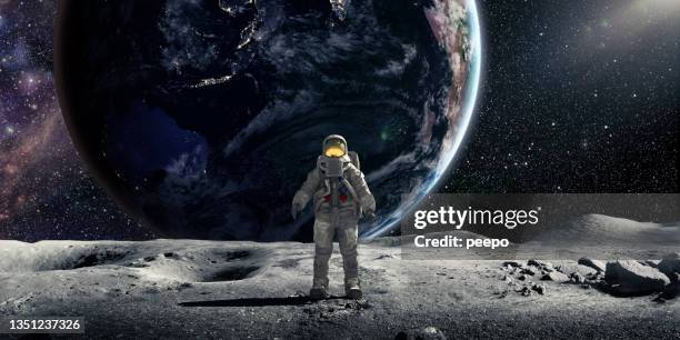 astronauta de pie en la luna mirando hacia la cámara con la tierra de fondo - superficie lunar fotografías e imágenes de stock