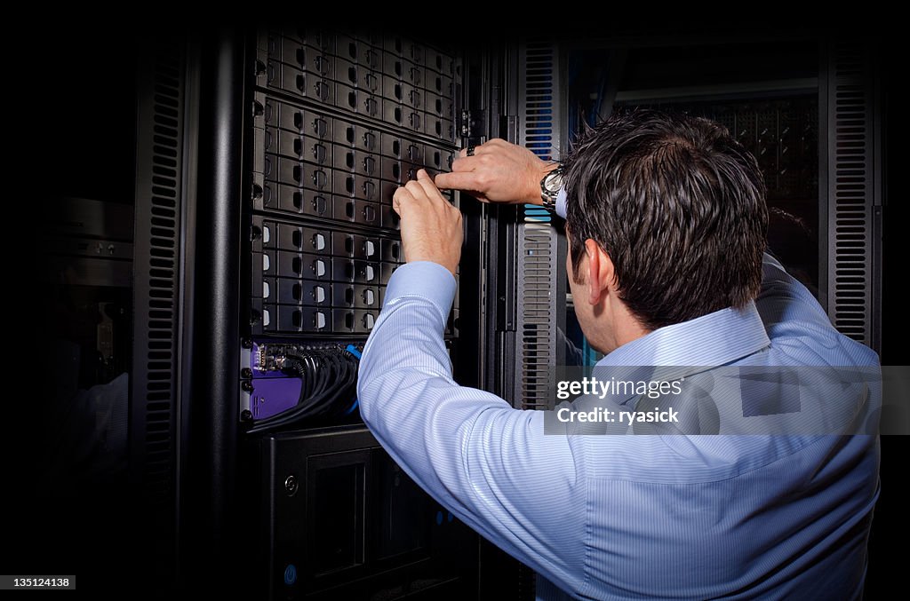 IT Technician From Behind Repairing Server in Network Bay