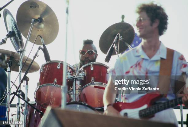 American actor and television personality Mr T wearing red-and-white framed glasses playing the drums for the Beach Boys, with a musician in shot, at...