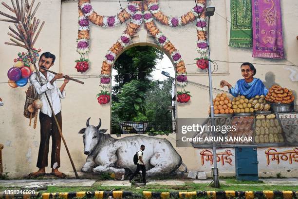 Man walks past a mural along a street in New Delhi on June 30, 2023.