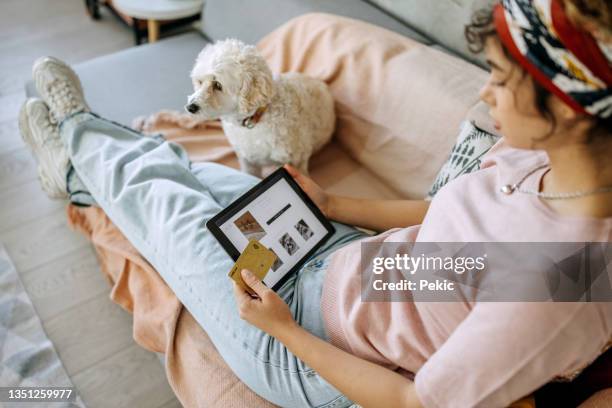 junge lässig gekleidete frau, die schmuck auf einem digitalen tablet kauft - shopping screen stock-fotos und bilder