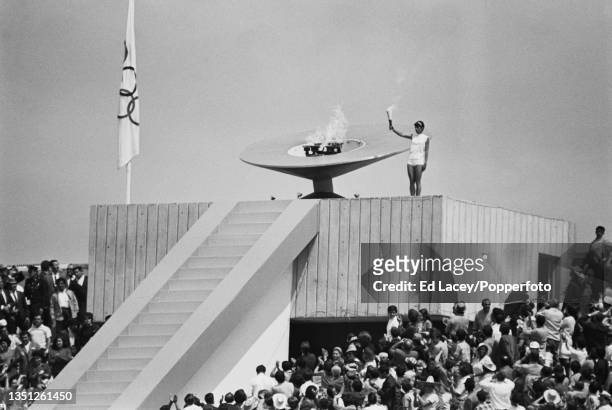 Mexican athlete Enriqueta Basilio holds aloft the Olympic torch flame after lighting the cauldron during the 1968 Summer Olympics opening ceremony...
