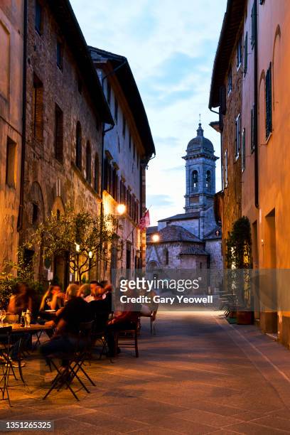 people sitting outside restaurants and bars along cobbled street at dusk - cobbled street stock pictures, royalty-free photos & images
