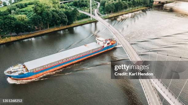 an aerial daytime view of a cargo ship under the nescio bridge - stock photo - bridge stock photos et images de collection