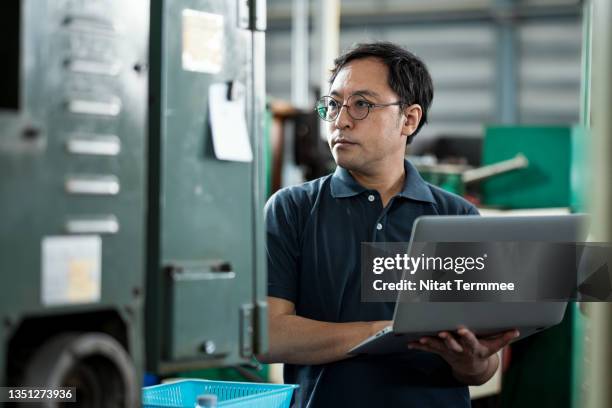 preventing machinery downtime in the manufacturing industry. senior maintenance engineer using a laptop for machinery analysis based on the operating condition to predict breakdowns and failures. - extração de dados - fotografias e filmes do acervo