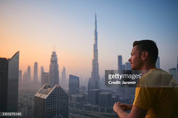 man enjoying calm during sunrise against urban skyline"n - dubai city stock-fotos und bilder