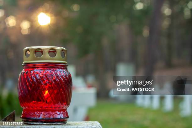 candle burning on grave in cemetery. - friedhof stock-fotos und bilder