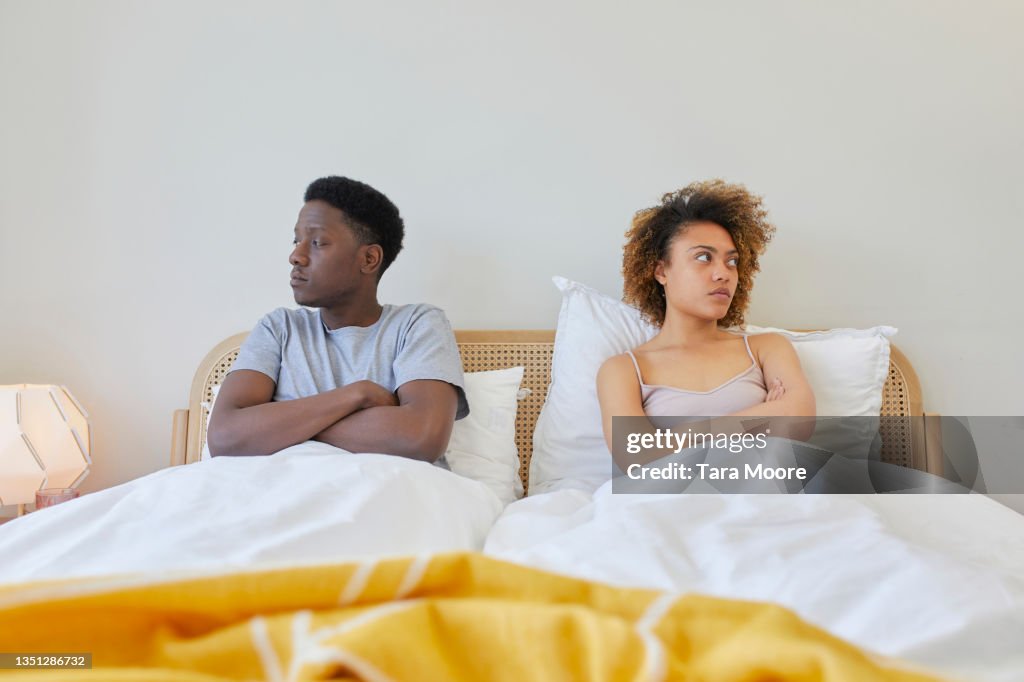 Young couple sitting next to each other in bed.
