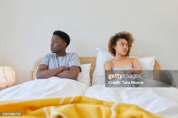 young couple sitting next to each other in bed. - fighting imagens e fotografias de stock