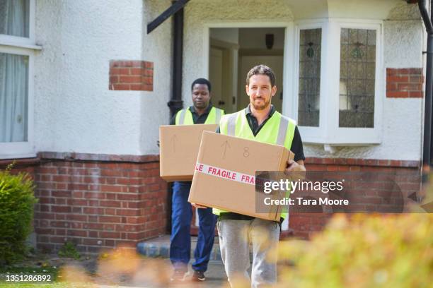 two removal men carrying boxes. - möbelpacker stock-fotos und bilder