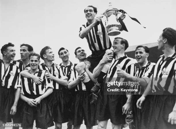 Newcastle United Football Club team captain Joe Harvey is carried on the shoulders of his celebrating team mates and holds the Football Association...