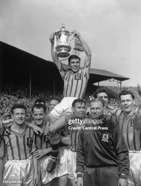 Aston Villa Football Club team captain Johnny Dixon is carried on the shoulders of his celebrating team mates and holds the Football Association...
