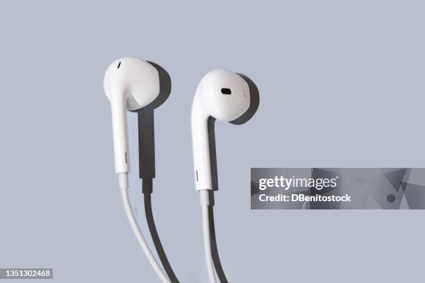 small white wired headphones, with hard shadow, on blue-gray background. concept of music, listening, radio, podcast, running and dancing. - ohrhörer stock-fotos und bilder