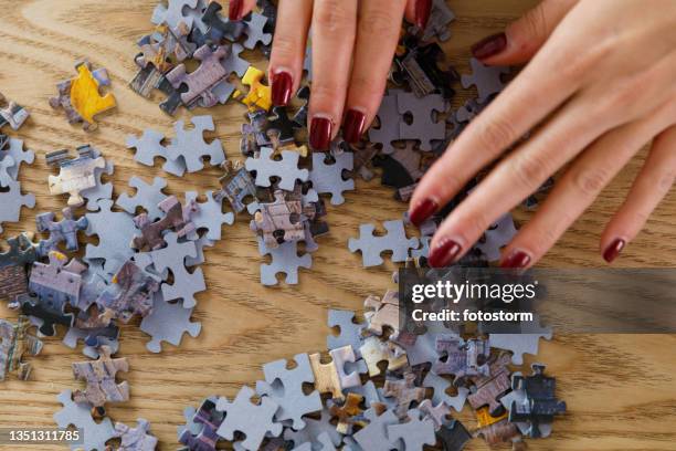 mains féminines arrangeant des pièces de puzzle - jigsaw piece stock photos et images de collection