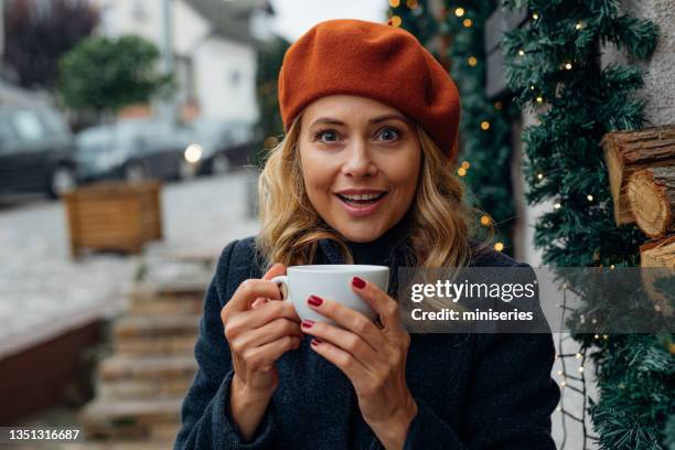 portrait of smiling woman enjoying in cup of tea while sitting in an outdoor cafe - christmas coffee stock pictures, royalty-free photos & images