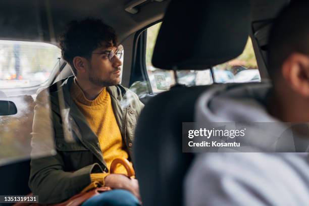 portrait of a worried young man in back seat of car looking out of window - taxi worried bildbanksfoton och bilder