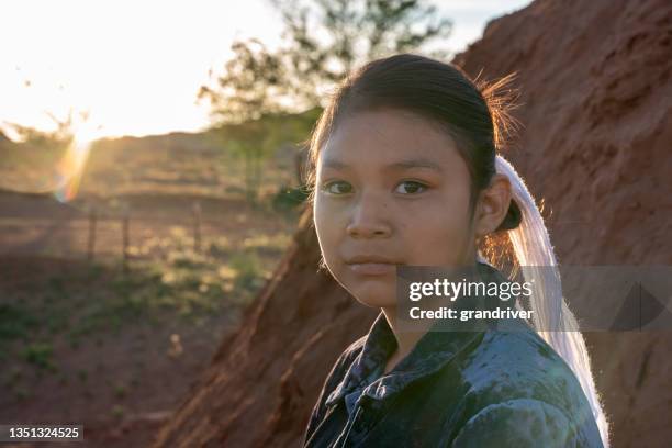 twelve year old native american navajo girl looking seriously at the camera in front of a traditional indian hogan at the monument valley tribal park at the arizona/utah border in the united states - traditional native american medicine stock pictures, royalty-free photos & images