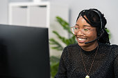 Customer service agent, financial advisor call center employee sits at desk in company in front of computer screen, headphones with microphone on ears, connecting with caller, solving problem