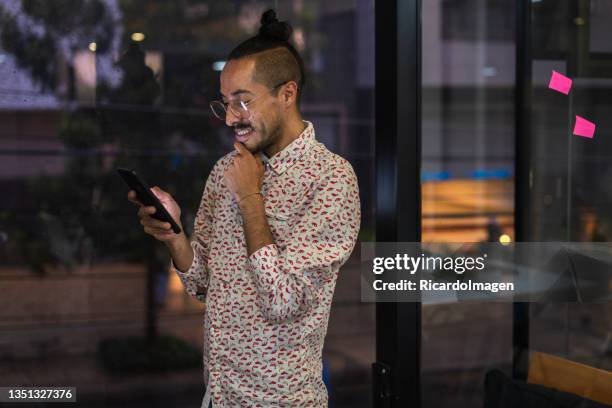 latin man essa in the office for which he works using his mobile phone - colombian culture stock pictures, royalty-free photos & images