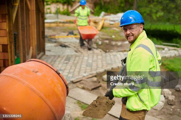 landscape contractor loading the cement mixer - construction worker stockfoto's en -beelden