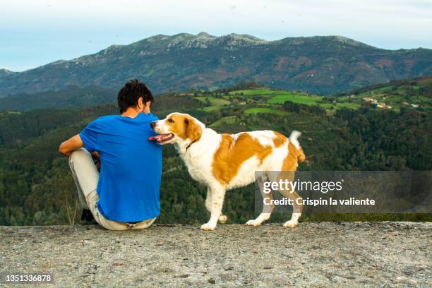 hombre joven sentado contemplando el paisaje con su cachorro - hombre sentado stockfoto's en -beelden