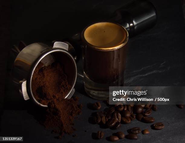 high angle view of coffee cup with beans and grinder on table - grinder stock-fotos und bilder