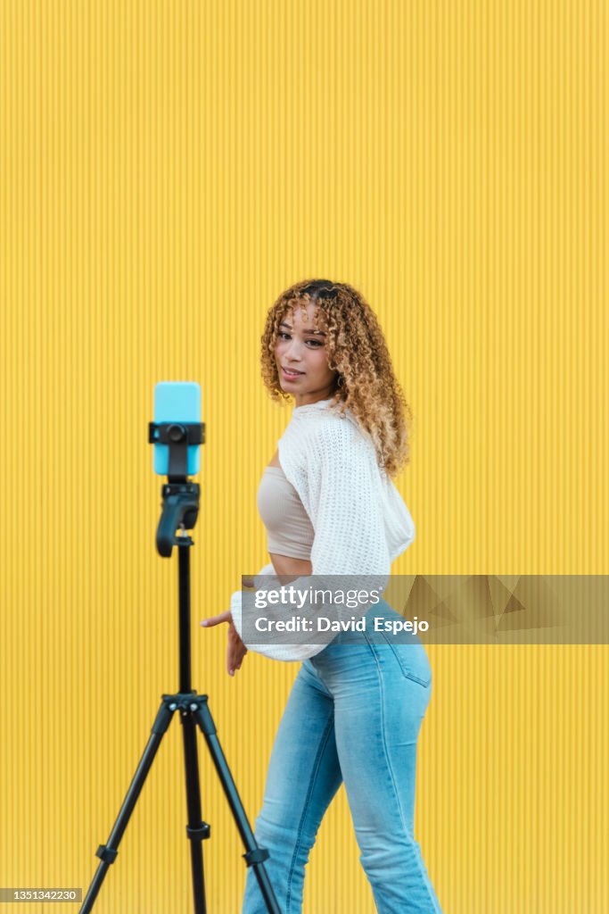 Carefree Hispanic woman recording video on street