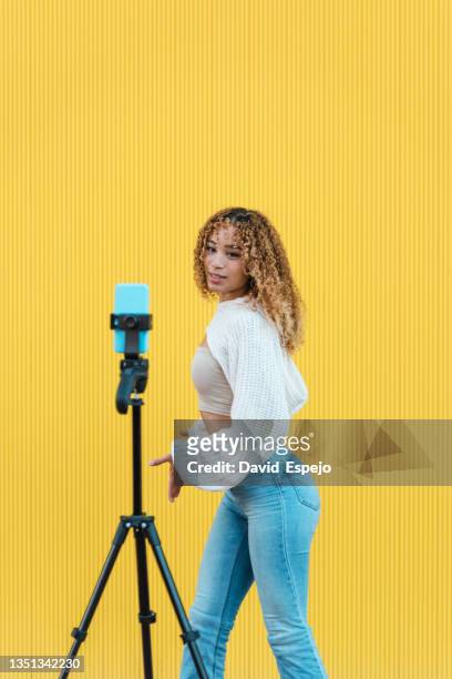 carefree hispanic woman recording video on street - clip stock pictures, royalty-free photos & images