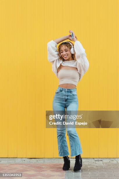 cheerful hispanic woman with smartphone listening to music - fashion pretty woman listening music in headphones with smartphone colorful stockfoto's en -beelden