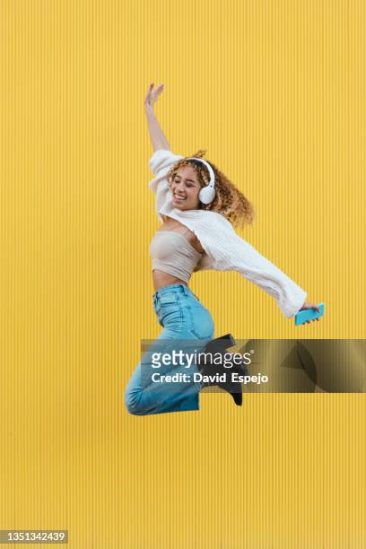 hispanic woman in headphones jumping on street - publicity event stockfoto's en -beelden