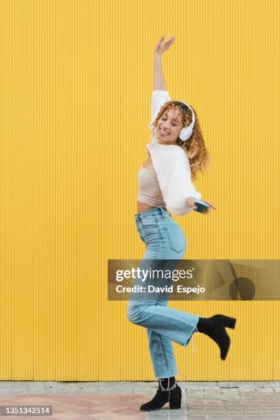 cheerful hispanic woman with smartphone listening to music - fashion pretty woman listening music in headphones with smartphone colorful stockfoto's en -beelden