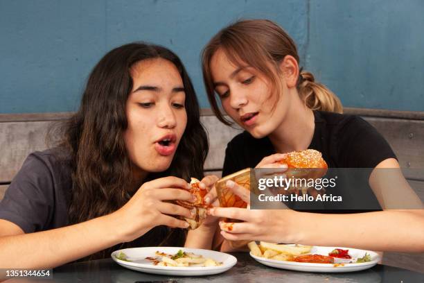 two beautiful young teenager girlfriends comparing burgers - eating competition stock pictures, royalty-free photos & images