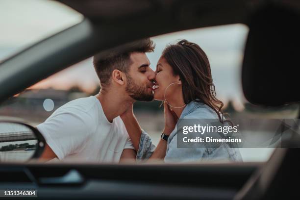 male kissing his girlfriend on date by the river - cute girlfriends stockfoto's en -beelden