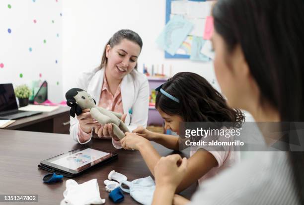 little girl playing with doll in psychologist office - victim help stock pictures, royalty-free photos & images