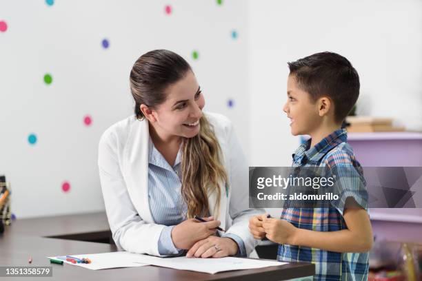 happy psychologist and little boy smiling at each other - psychotherapy stock pictures, royalty-free photos & images