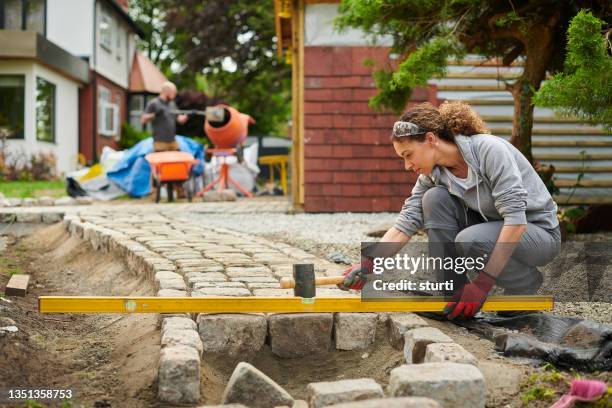 propietario instalando un camino empedrado - loseta fotografías e imágenes de stock