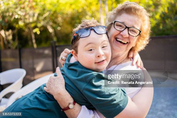 portrait of grandmother and grandson in back yard. - down syndrome care stockfoto's en -beelden