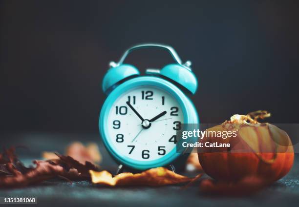 teal alarm clock with fall decorations for daylight savings time - daylight saving time stock pictures, royalty-free photos & images