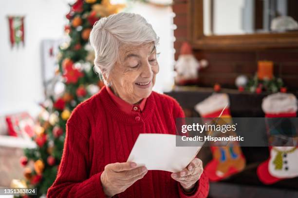 portrait of beautiful senior woman at home reading a christmas card she received looking very happy and smiling - only senior women stock pictures, royalty-free photos & images