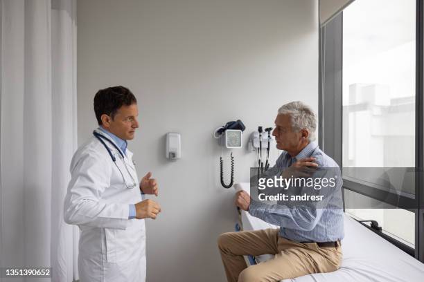 senior man vising the doctor to check a pain in his shoulder - orthopedist stock pictures, royalty-free photos & images