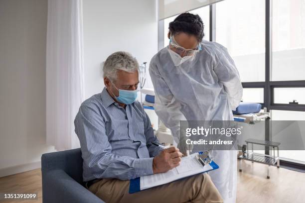 man filling a form for a procedure at the hospital - biosecurity stock pictures, royalty-free photos & images